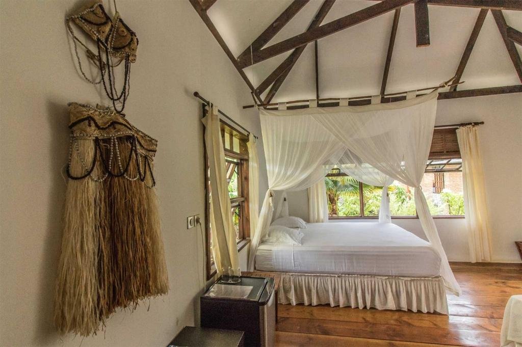 Light and airy guest room with canopy bed at Le Coconut Lodge