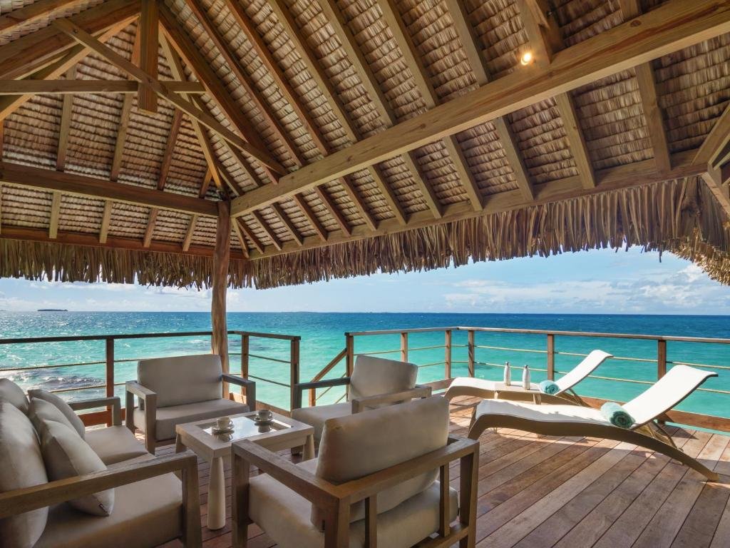 Outdoor terrace at Le Tikehau by Pearl Resorts with lounge chairs overlooking turquoise lagoon