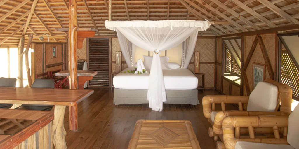 Open air bungalow interior with canopy bed at Tevahine Dream Rangiroa