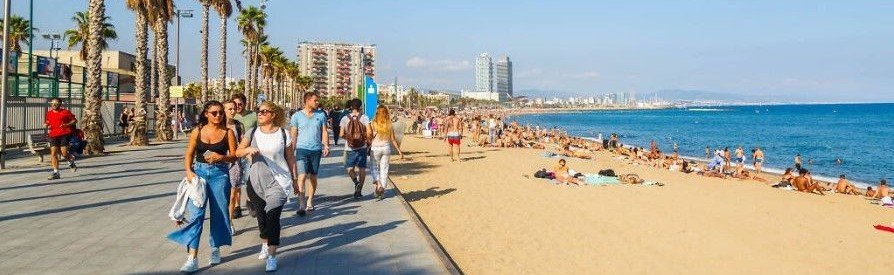 Barceloneta Beach in Barcelona with promenade, palm trees, and people along the Mediterranean coast