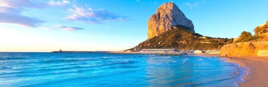 Penon de Ifach at sunset over Calpe beach with calm turquoise Mediterranean Sea on the Costa Blanca Spain