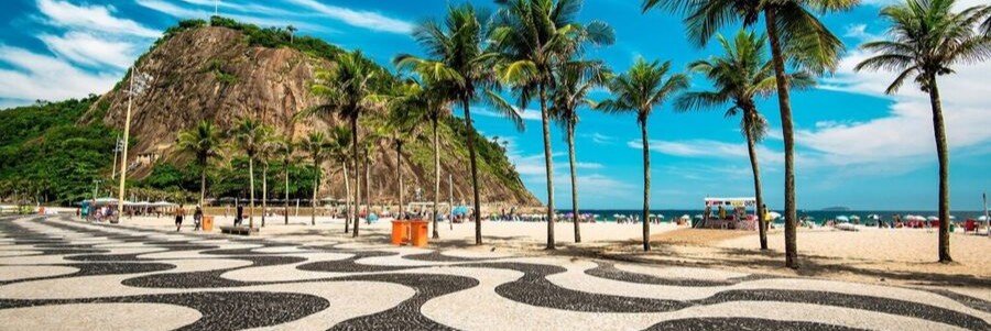 Black and white mosaic promenade along Copacabana Beach in Rio de Janeiro with palm trees and ocean views.