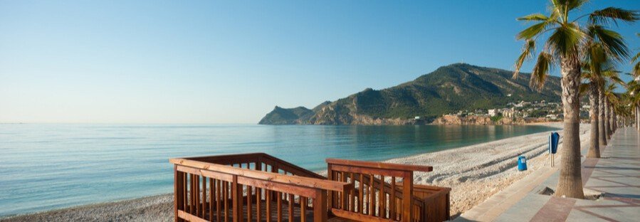 Costa Blanca Spain beach with palm-lined promenade and calm sea views
