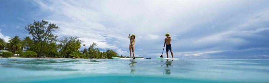 Two people paddleboarding on clear turquoise water in Fakarava French Polynesia