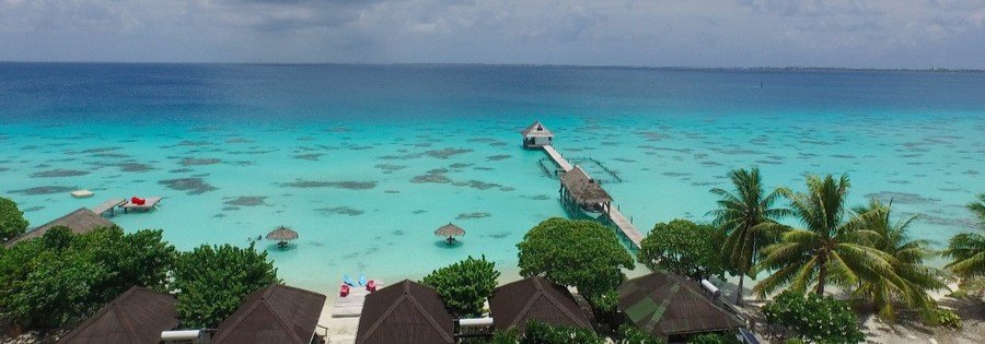 Turquoise lagoon with overwater pier and bungalows at Havaiki Lodge in Fakarava French Polynesia