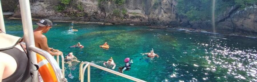People snorkeling in clear water from boat in tropical cove Martinique