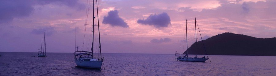 Sailboats at sunset on calm ocean with island silhouette in Martinique