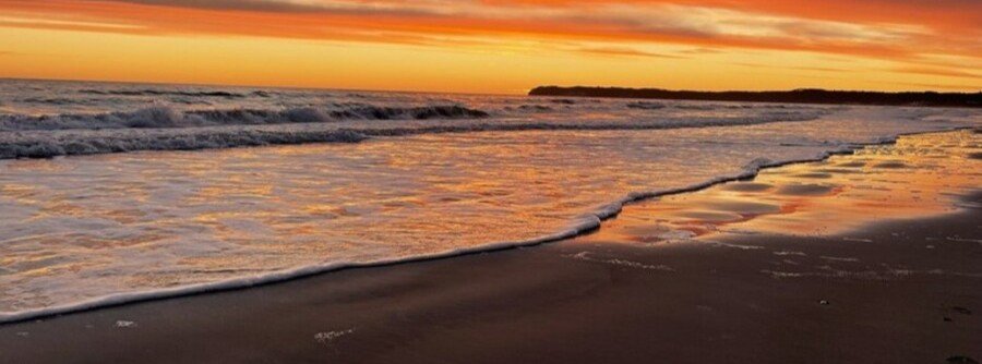 Sunset over Prora Beach on Rügen Island Germany with waves along the Baltic Sea shoreline.