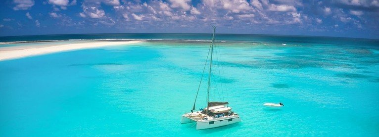 Catamaran boat anchored in Rangiroa lagoon with bright turquoise water and a white sandbar in the distance