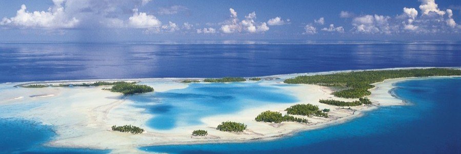 Aerial view of Rangiroa lagoon in French Polynesia with turquoise water, sandy motus, and surrounding deep blue ocean.