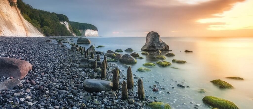White chalk cliffs and rocky Baltic shoreline in Sassnitz Rügen Germany near Jasmund National Park at sunset.