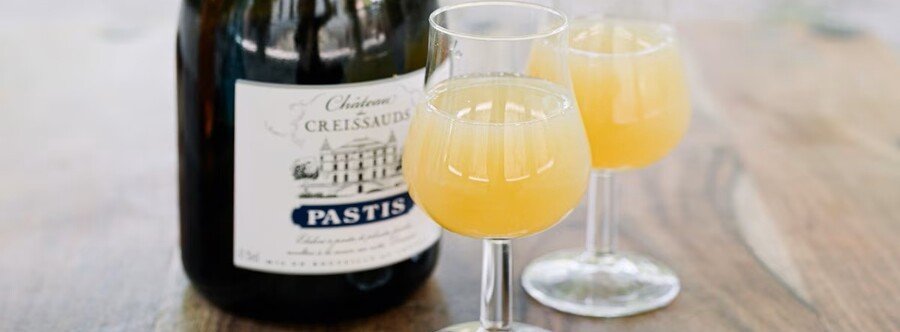 Glasses of flavored pastis with cloudy yellow color served alongside a bottle in Marseille