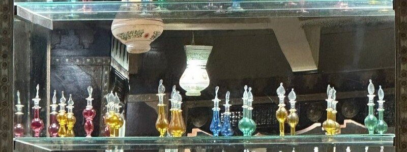 A shelf display of small, colorful hand-blown glass perfume bottles in a traditional market shop near the Alexandria Waterfront.