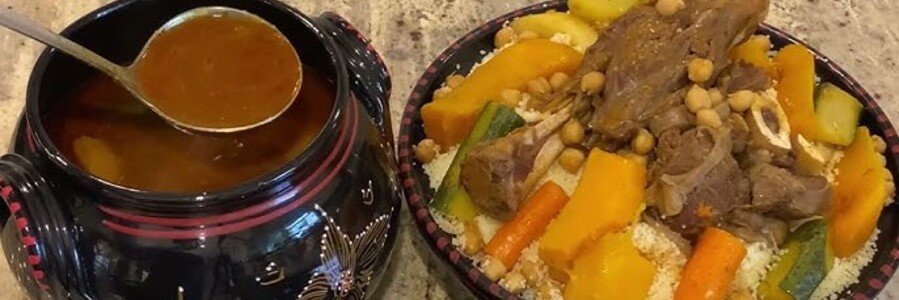Traditional Algerian couscous with lamb, vegetables, chickpeas, and broth served in decorative dishes.