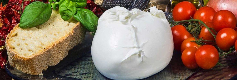 A fresh ball of buffalo mozzarella sliced open to reveal a creamy center, served with local tomatoes.
