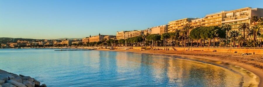 Golden hour view of Plage Macé along La Croisette in Cannes with calm Mediterranean water and palm-lined promenade