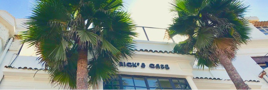 Exterior of Rick’s Café near Casablanca Port with palm trees and classic whitewashed architecture.
