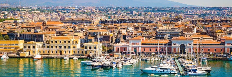 Catania Port Sicily coastal cliffs with clear blue water and dramatic rock formations along the coast