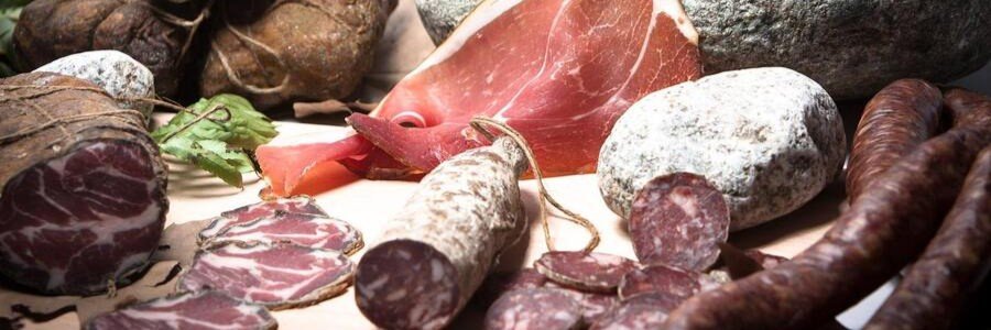 Corsican charcuterie with cured meats, sausages, and sliced ham on a rustic table