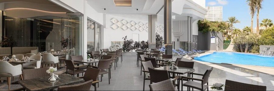 Modern outdoor patio and dining area next to a bright blue swimming pool at the Crowne Plaza Alexandria Mirage.