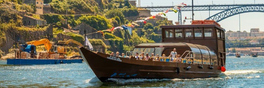 traditional river boat cruising along Douro River with Porto city and bridge views