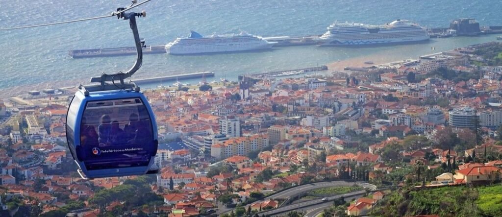 Panoramic view from the Funchal Cable Car overlooking cruise ships docked at Funchal Port and the red-roofed city of Madeira.