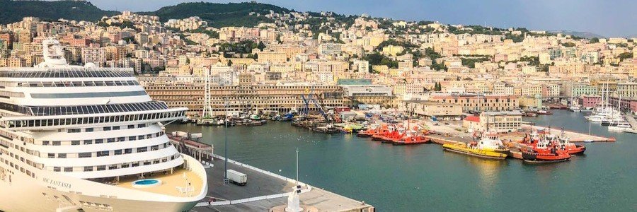 Cruise ship docked at Genoa port with city skyline and harbor views in Italy