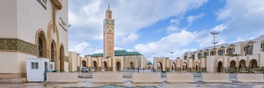 Grand courtyard view of Hassan II Mosque near Casablanca Port with marble plaza and towering minaret.