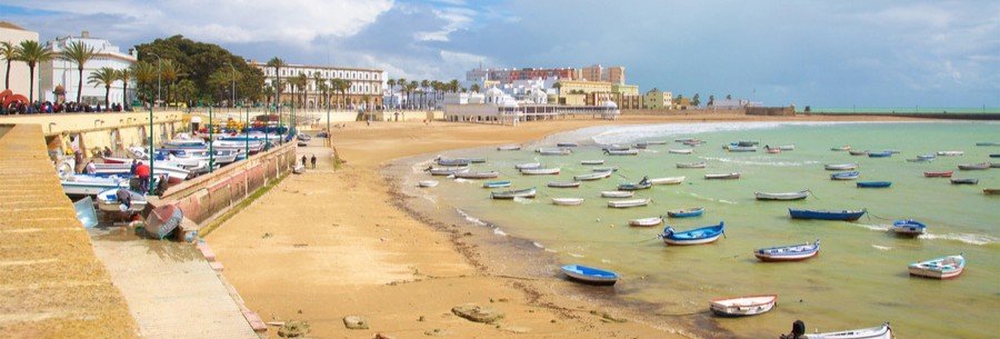 La Caleta Beach Málaga with colorful boats and clear shallow water along the coast