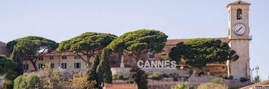 Le Suquet hill in Cannes with clock tower, trees, and Cannes sign overlooking the Old Town