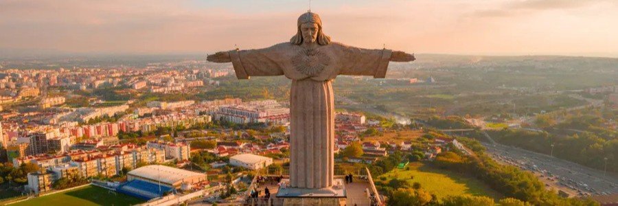 Aerial view of the Sanctuary of Christ the King statue overlooking the Lisbon Port and the beautiful Tagus Coast at sunset.