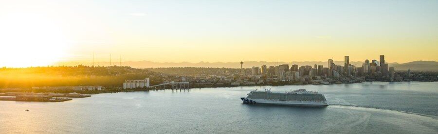 Cruise ship leaving Livorno port at sunset with city skyline