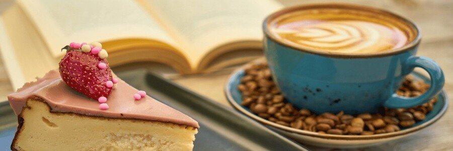 Málaga coffee with latte art and slice of cake topped with strawberry