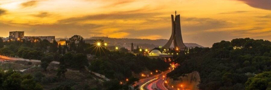 Sunset view of Martyrs’ Memorial in Algiers with city lights and dramatic evening skies.