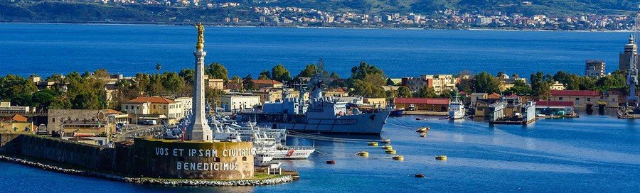 Messina port harbor in Sicily with statue and cruise ships along the waterfront