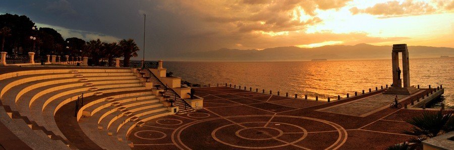 Sunset over Messina harbor with waterfront promenade