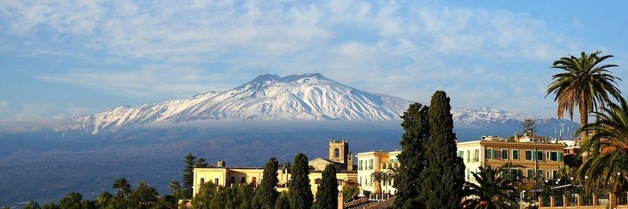 Mount Etna volcano towering over Sicily landscape with snow on peak