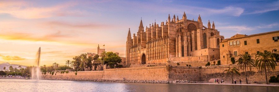 Palma Cathedral at sunset in Mallorca with warm light reflecting over the waterfront