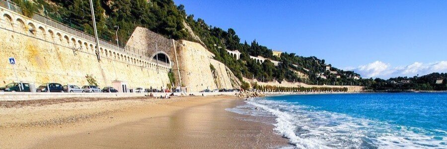 Plage des Marinières wide beach with turquoise water and train tracks along the coast in Villefranche-sur-Mer France