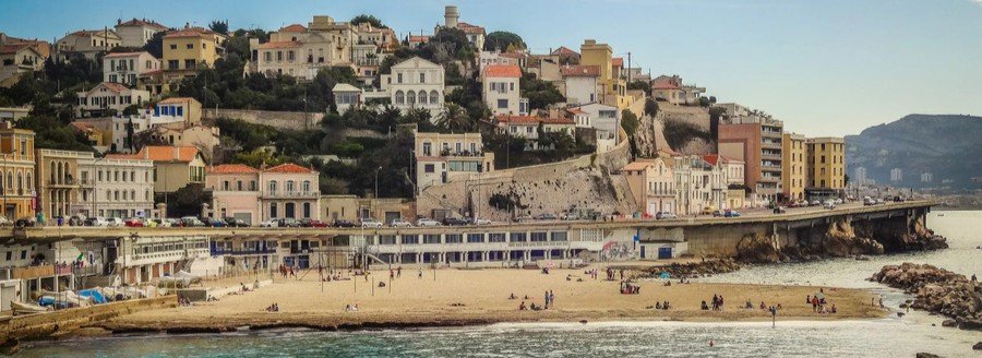 Plage du Prophète beach in Marseille with sandy shore and hillside homes along the Mediterranean coast