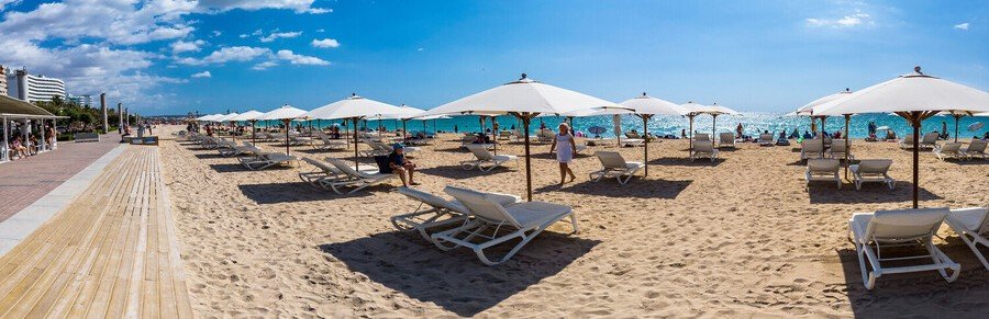 Playa de Palma beach in Mallorca with sunbeds, umbrellas, and clear Mediterranean water