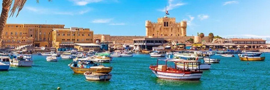 Small colorful boats floating in the harbor at Port Said Egypt with historic waterfront buildings and Mediterranean views near the Suez Canal.