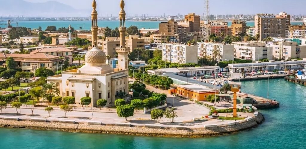 Aerial view of Port Said Egypt featuring turquoise waterfront views, a mosque with tall minarets, and the busy harbor along the Suez Canal.