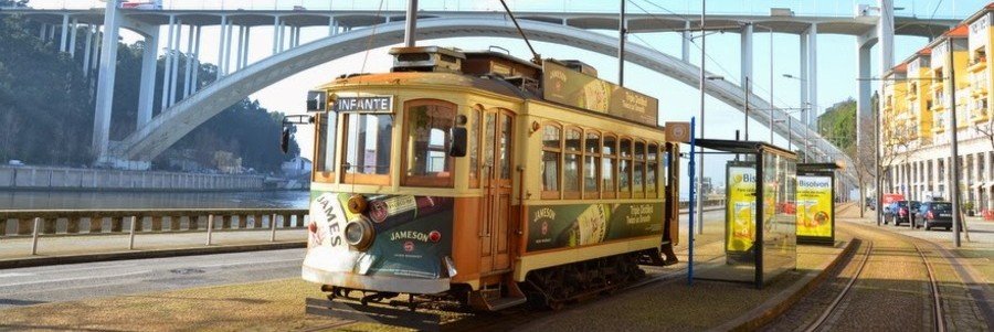 historic tram-style Bus 500 near Porto Port with Dom Luis I Bridge in the background