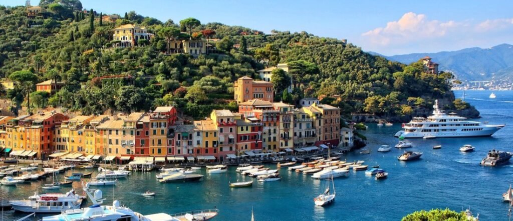 Panoramic view of Portofino Port featuring colorful houses, luxury yachts, and the lush hills of the Italian Riviera.