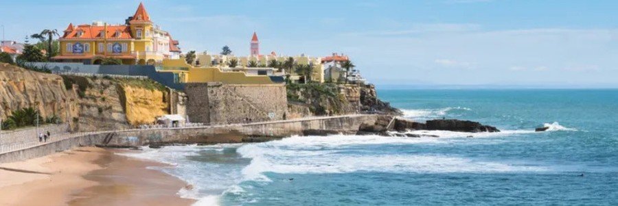 Colorful cliffside buildings overlooking a scenic beach with waves crashing below