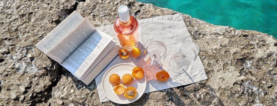 provence rose wine picnic by the sea with glasses and snacks on rocky coastline in the French Riviera