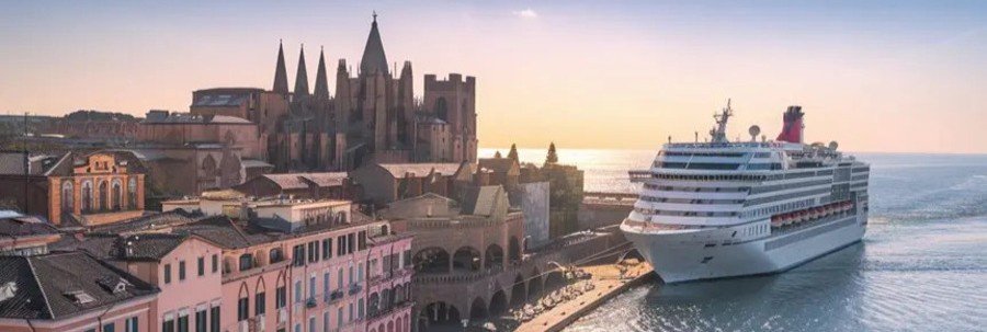 Large white cruise ship docked at the modern Salerno pier with the city's historic cathedral and hills in the background.