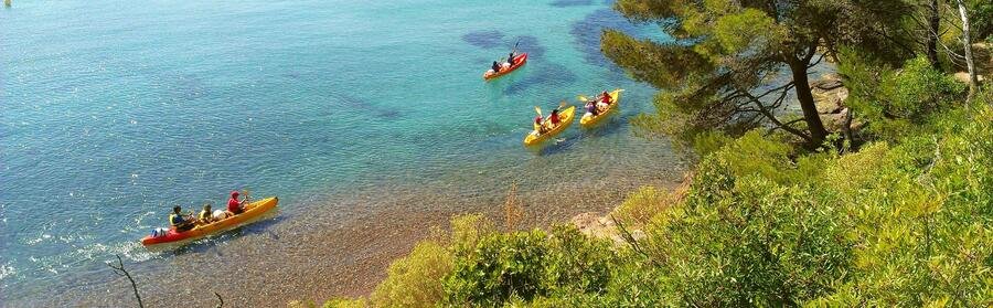 People kayaking in clear turquoise water along the Cannes coastline on the French Riviera