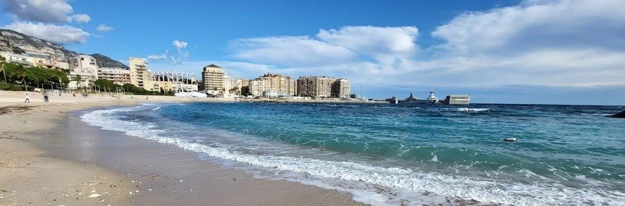Solarium Beach Monaco with waves along the coastline and city buildings in the background